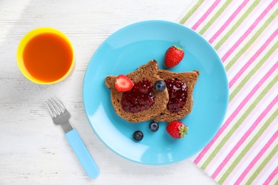 Photo of Tasty toasts served with jam, berries and juice on white wooden table, flat lay. Creative idea for kids breakfast