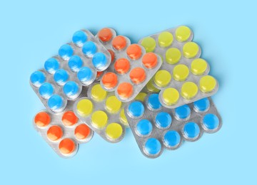 Photo of Blisters with cough drops on light blue background, flat lay