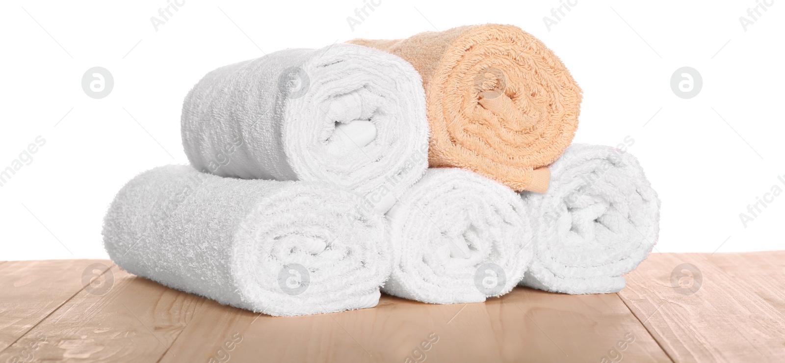 Photo of Soft colorful terry towels on wooden table against white background