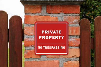 Image of Sign with text Private Property No Trespassing on brick column of wooden fence