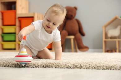 Photo of Children toys. Cute little boy playing with spinning top on rug at home, space for text