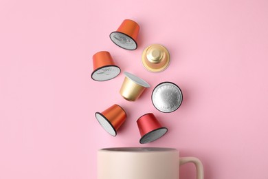 Many coffee capsules and cup on pink background, top view