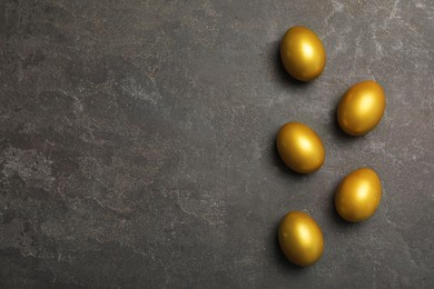 Golden eggs on black table, flat lay. Space for text