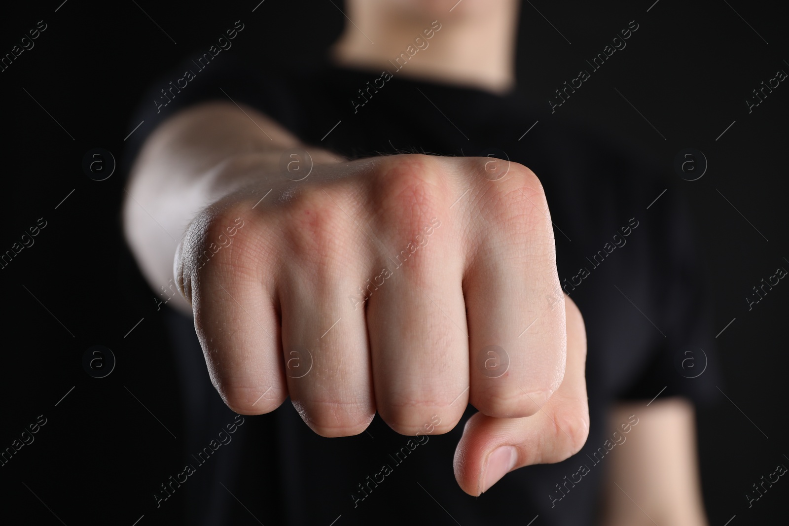 Photo of Man showing fist with space for tattoo on black background, selective focus
