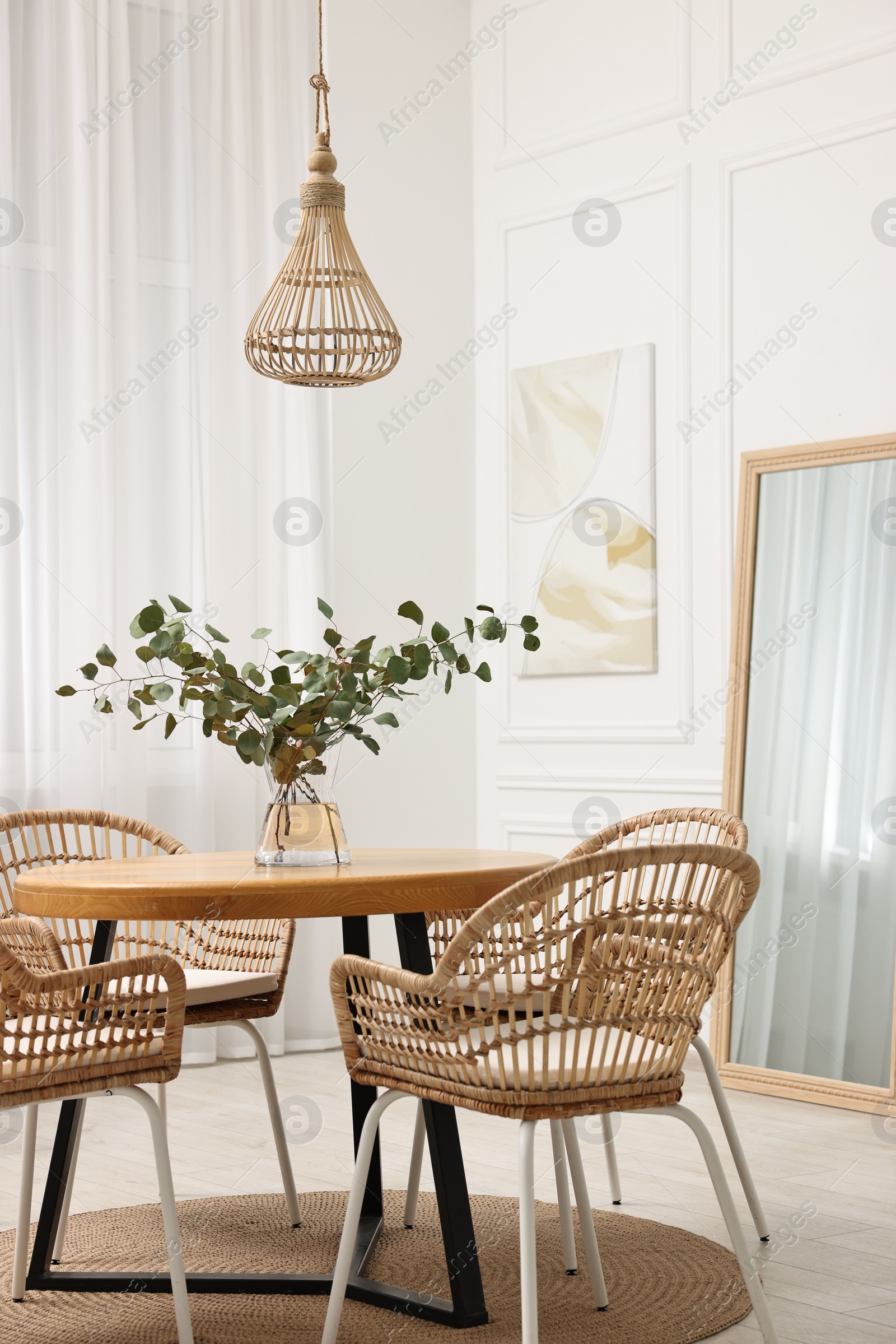 Photo of Dining room interior with comfortable furniture and eucalyptus branches