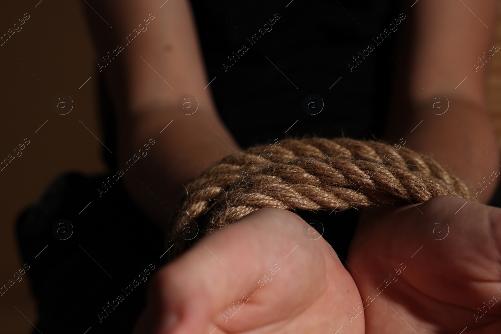 Photo of Little boy with tied arms taken hostage on dark background, closeup