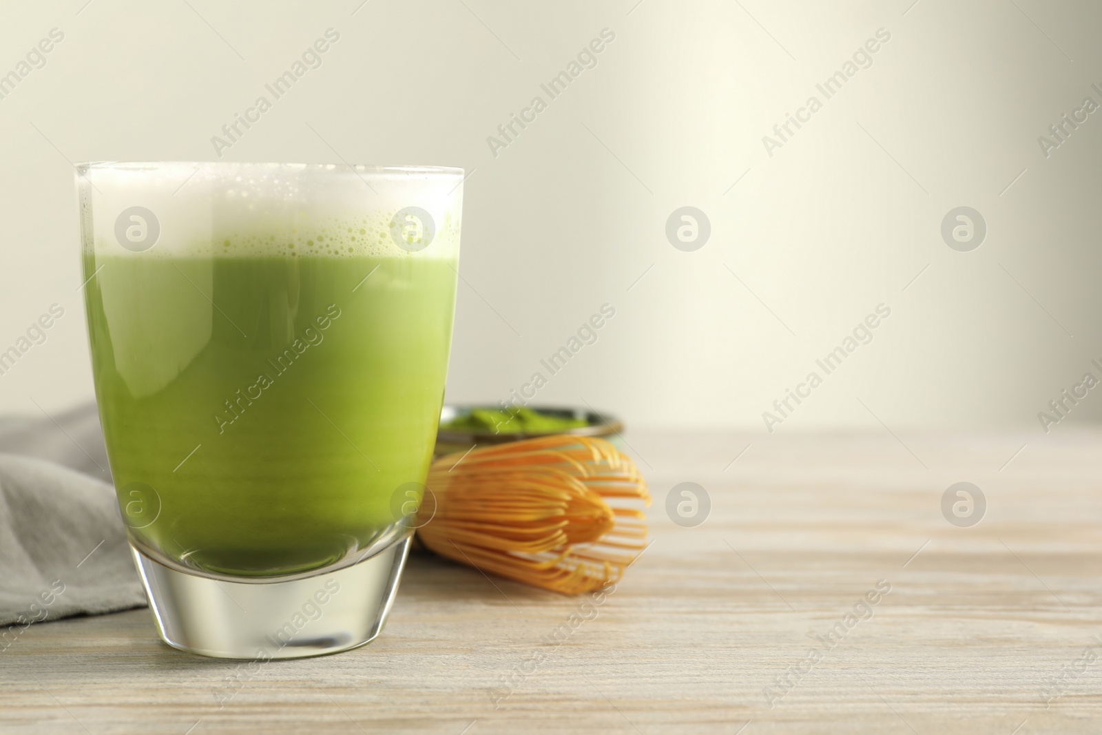 Photo of Glass of tasty matcha latte on wooden table, space for text