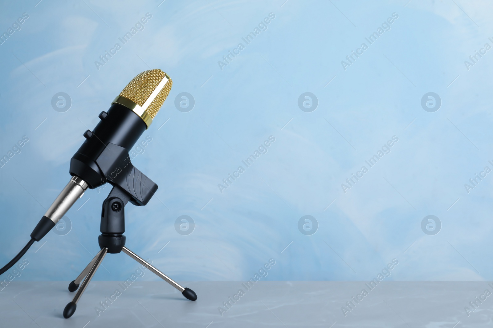 Photo of Microphone on table against color background. Space for text