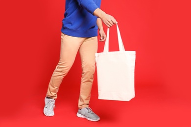 Photo of Young man with eco bag on red background, closeup