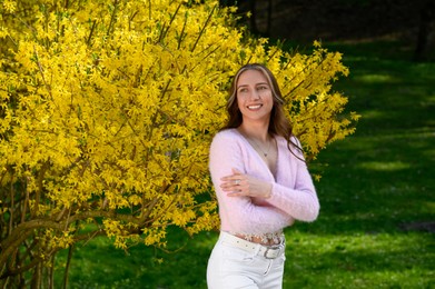 Photo of Beautiful young woman near blossoming shrub on spring day, space for text