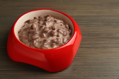 Wet pet food in feeding bowl on wooden background