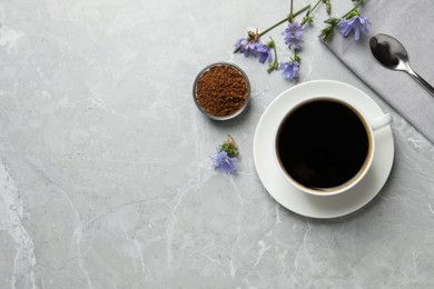 Cup of delicious chicory drink, granules and flowers on light grey marble table, flat lay. Space for text