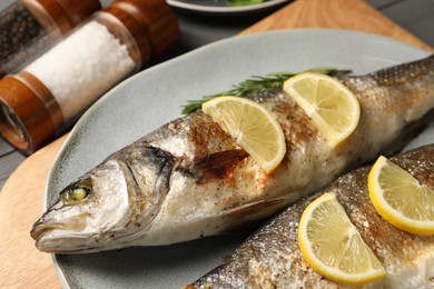 Photo of Delicious baked fish, lemon and rosemary on table, closeup