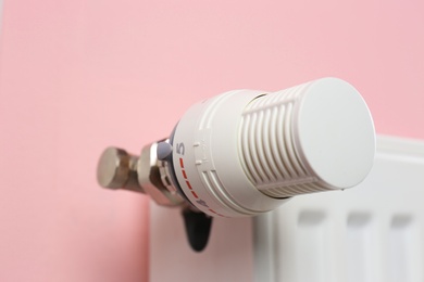 Photo of Heating radiator with thermostat on color background