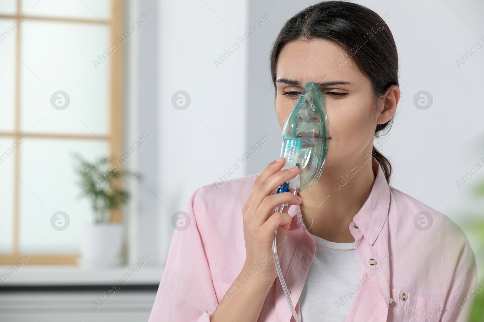 Photo of Sick young woman using nebulizer at home, space for text