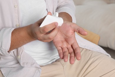 Man applying hand cream from tube at home, closeup