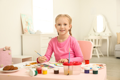 Cute little child painting at table in room