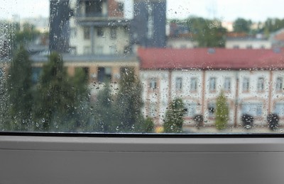 Photo of Wet window on rainy day, closeup. View from inside