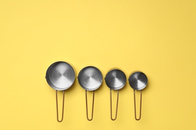 Photo of Different saucepans on yellow background, flat lay with space for text. Cooking utensils