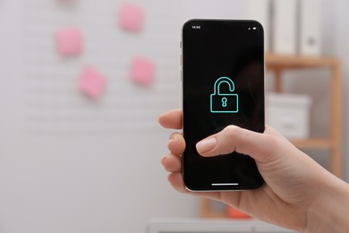 Woman holding smartphone with blocked screen indoors, closeup. Space for text