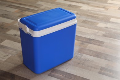 Closed blue plastic cool box on wooden floor