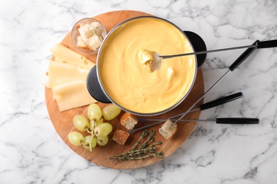 Photo of Flat lay composition with pot of delicious cheese fondue on marble table