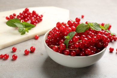Photo of Delicious red currants and mint in bowl on light grey table