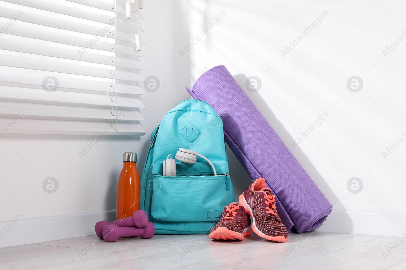 Photo of Backpack and sports equipment on floor indoors