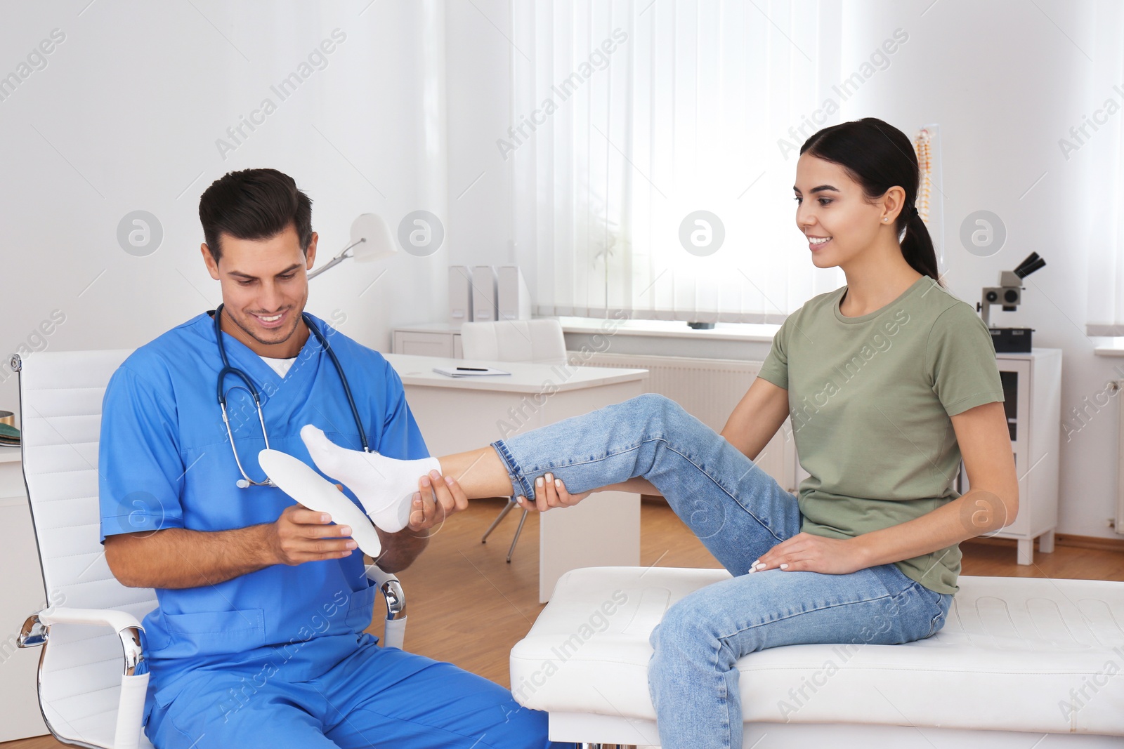 Photo of Male orthopedist fitting insole on patient's foot in clinic