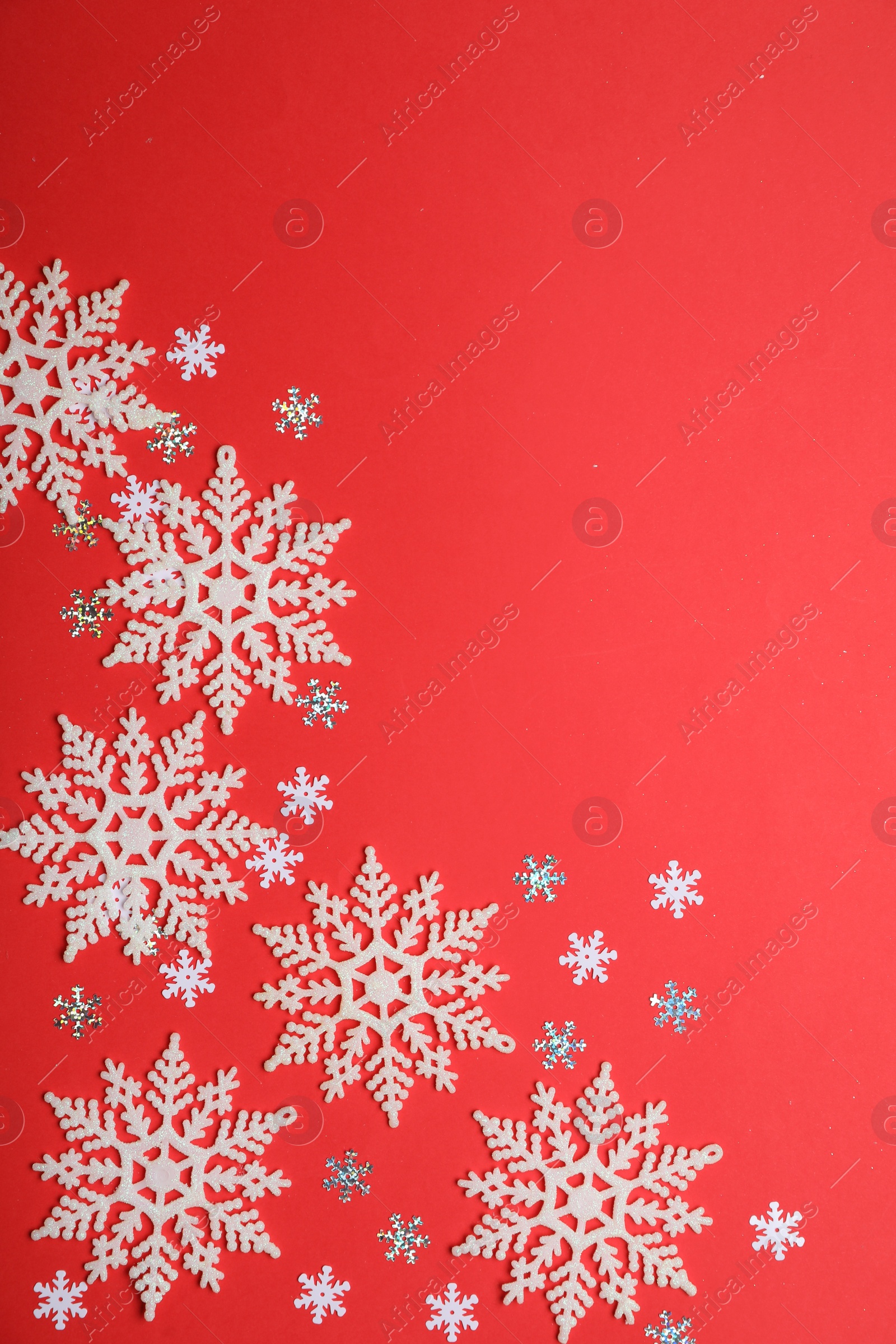 Photo of Beautiful decorative snowflakes on red background, flat lay. Space for text