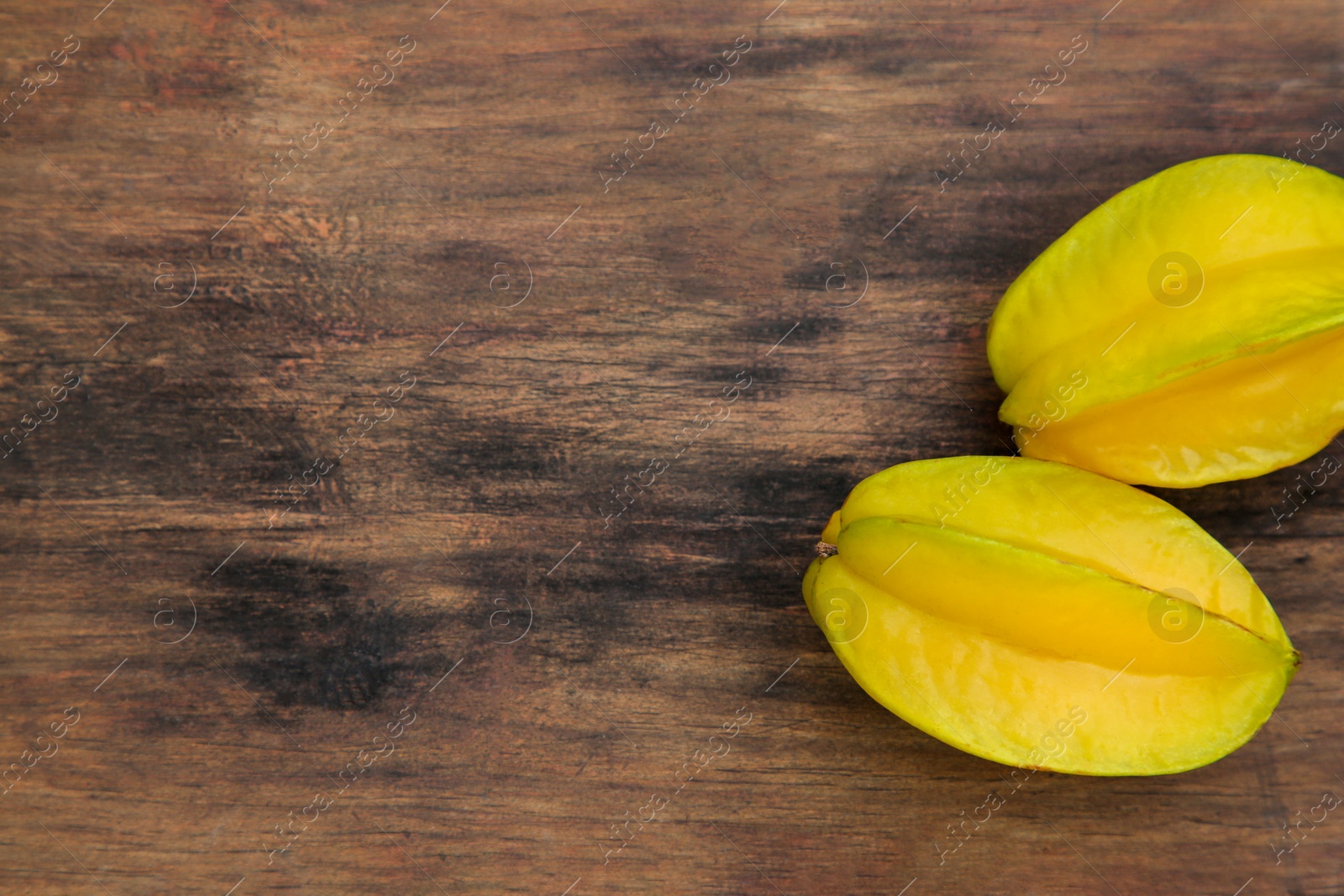 Photo of Delicious ripe carambolas on wooden table, flat lay. Space for text