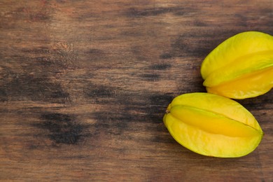 Delicious ripe carambolas on wooden table, flat lay. Space for text