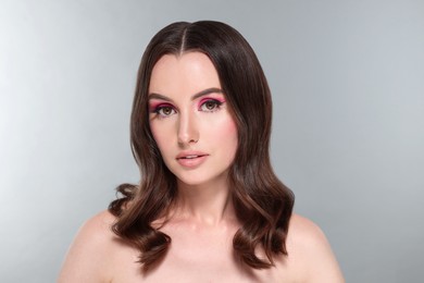 Photo of Portrait of beautiful young woman with makeup and gorgeous hair styling on light grey background