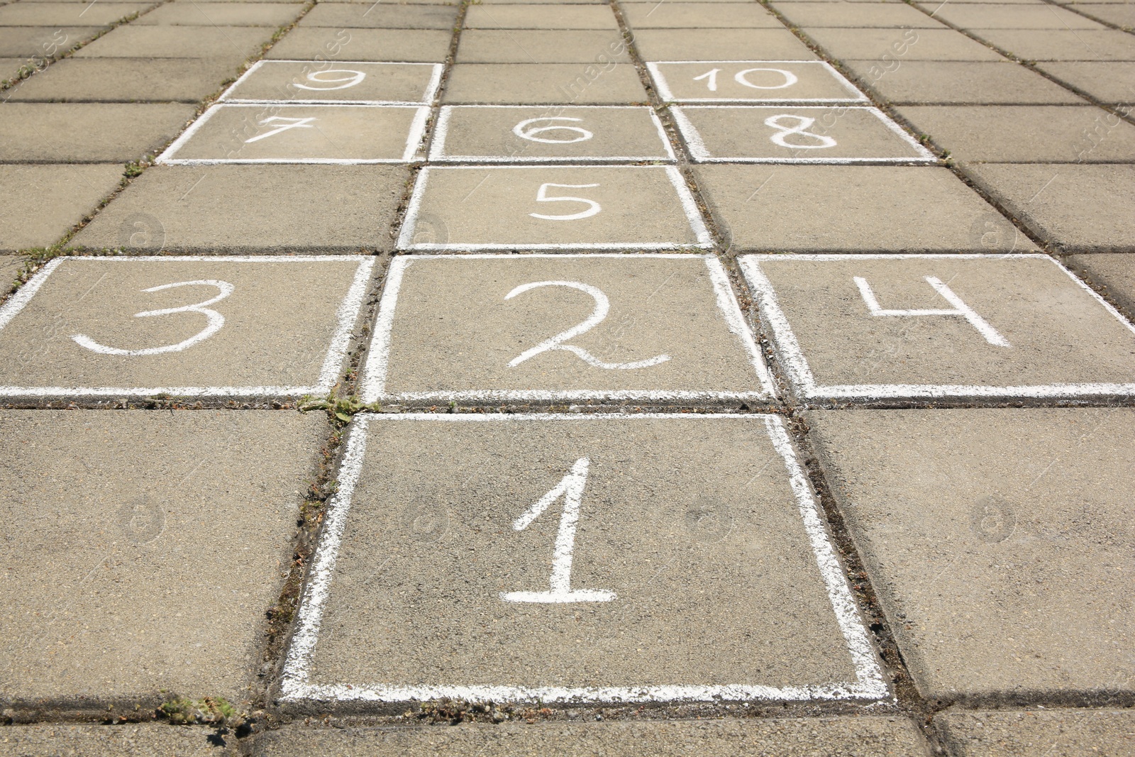 Photo of Hopscotch drawn with white chalk on street tiles outdoors