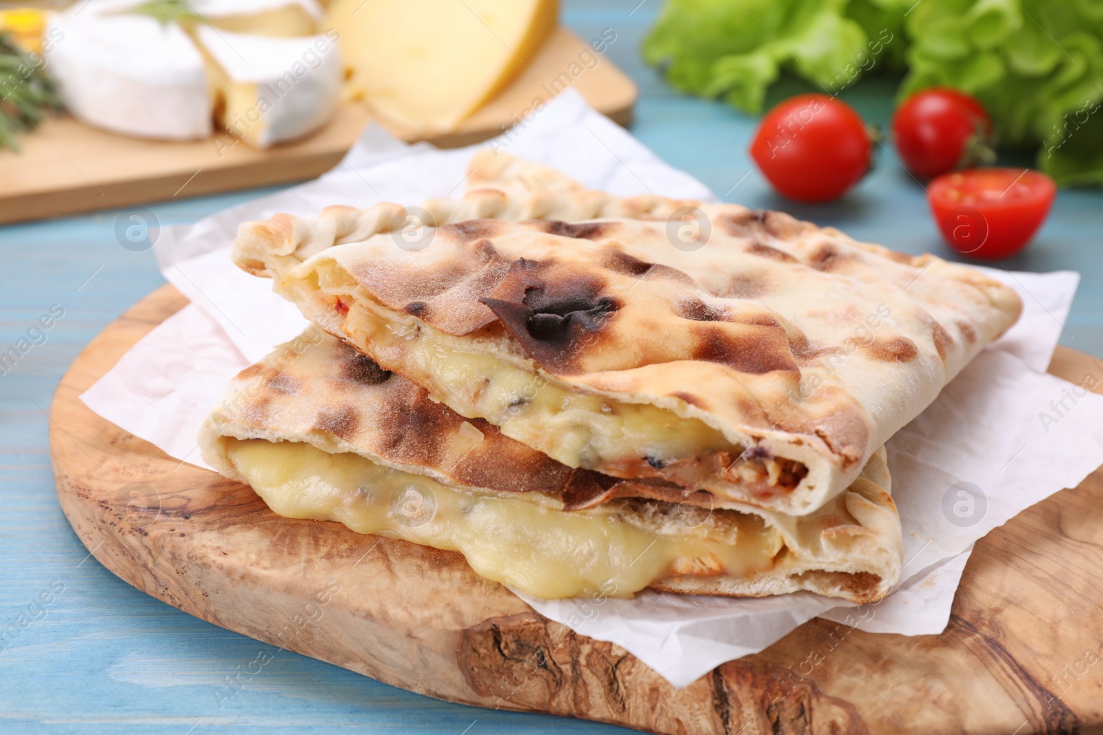 Photo of Tasty pizza calzones with cheese on light blue wooden table, closeup