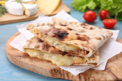 Tasty pizza calzones with cheese on light blue wooden table, closeup