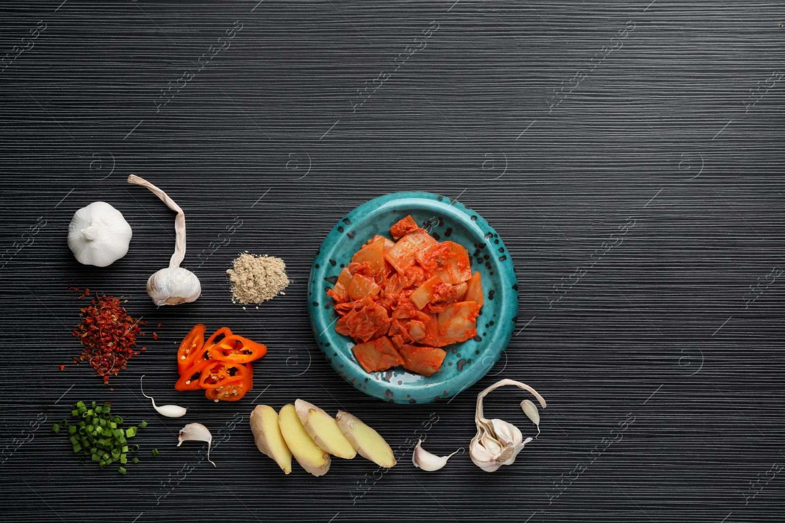 Photo of Flat lay composition with cabbage kimchi and ingredients on black wooden table, space for text