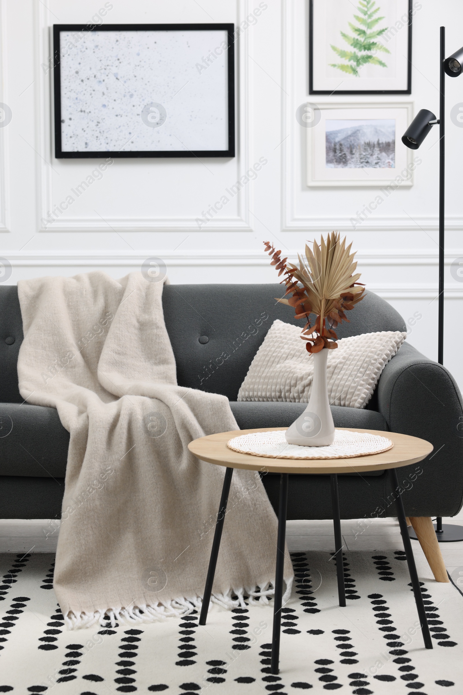 Photo of Stylish living room interior with comfortable sofa, blanket and side table