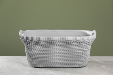 Photo of Empty plastic laundry basket near light green wall