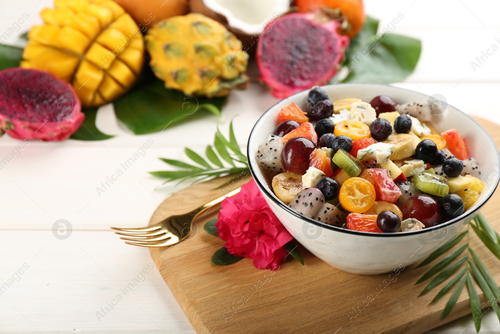 Photo of Delicious exotic fruit salad served on white table. Space for text