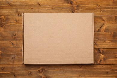 Closed cardboard box on wooden background, top view