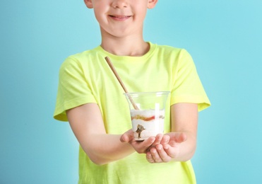 Little boy with yogurt on color background