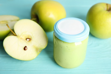 Photo of Jar with baby food and fresh apples on light blue wooden table