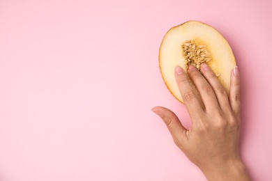 Photo of Young woman touching half of melon on pink background, top view with space for text. Sex concept
