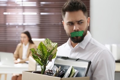 Dismissed man with taped mouth in office. Speech censorship