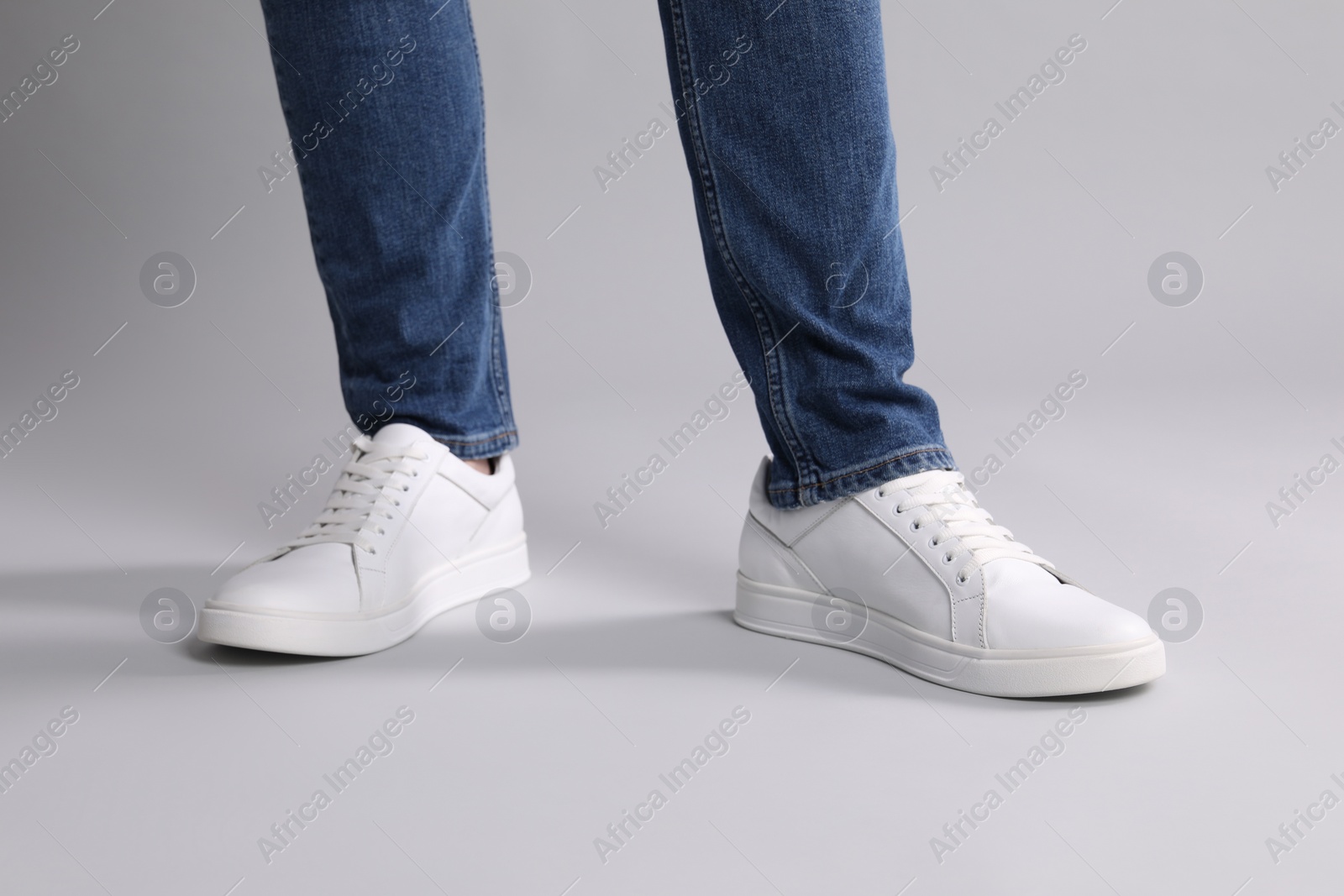 Photo of Man wearing stylish white sneakers on grey background, closeup