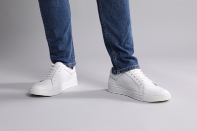 Photo of Man wearing stylish white sneakers on grey background, closeup