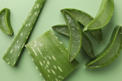 Photo of Cut aloe vera leaves on green background, flat lay