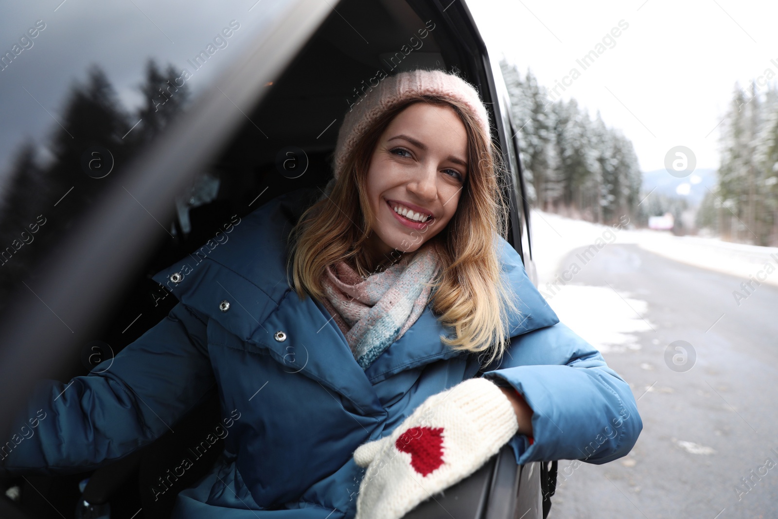 Photo of Young woman driving car and looking out of window on road. Winter vacation