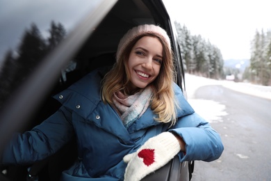 Young woman driving car and looking out of window on road. Winter vacation